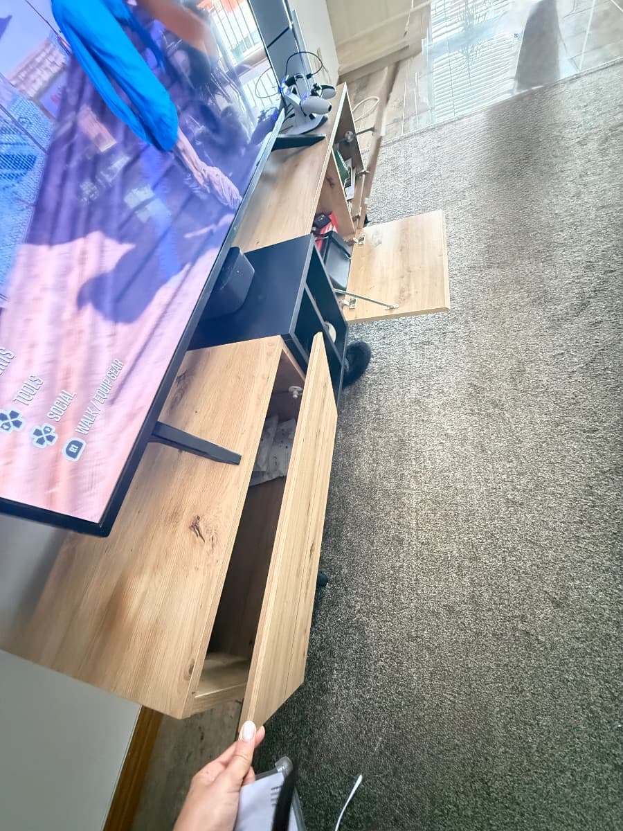 Móvel de TV em madeira carvalho e preto com compartimentos abertos e gavetas